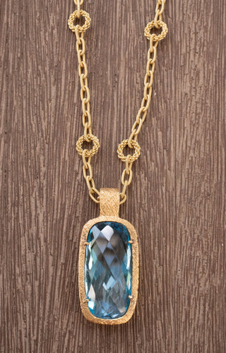 Indulge in the ultimate luxury with this 18K Yellow Gold Chain and Elongated Cushion Blue Topaz Pendant. The chain, crafted in Vicenza, Italy, and stamped 1395VI, is a masterpiece of Italian goldsmithing, measuring a classic 18 inches in length. Suspended from the chain is a breathtaking elongated cushion-cut blue topaz (30x15mm), showcasing a mesmerizing checkerboard faceting pattern that captures and reflects light with unparalleled brilliance.

This piece is perfect for those who appreciate fine craftsma